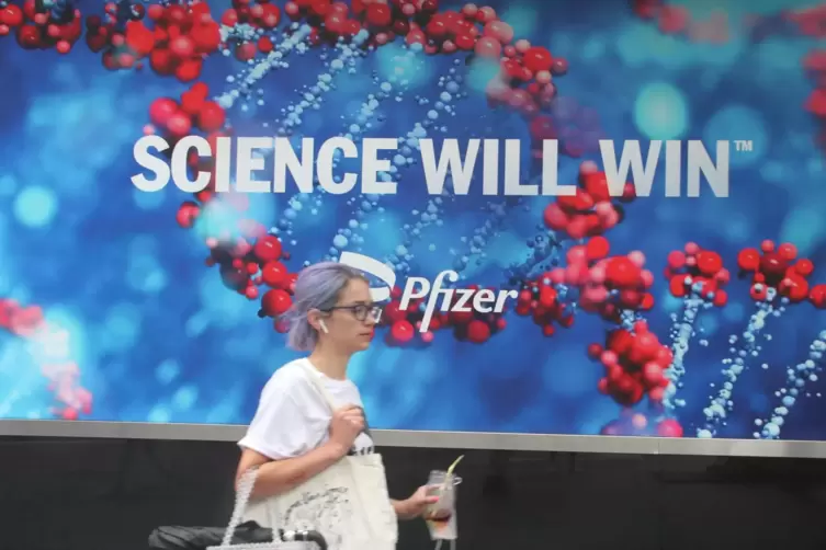 Eine New Yorkerin vor einem Werbeplakat von Pfizer. 
