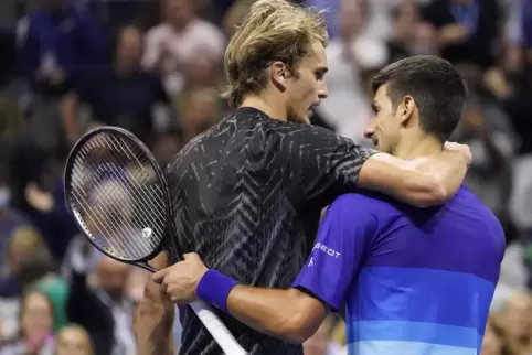 Novak Djokovic (r) und Alexander Zverev umarmen sich.