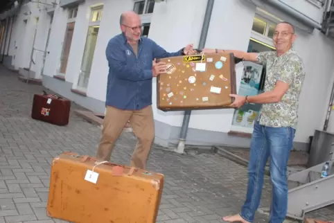 Auktionator Klaus Zahneißen (li.) übergibt einen der ersteigerten Koffer an Guido Pausch vom Gewerbeverband.