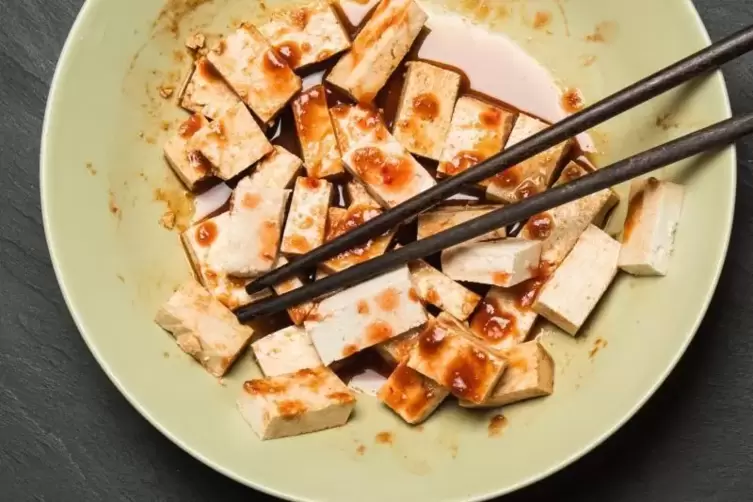 Tofu mit Marinade und Stäbchen in einer Schüssel.