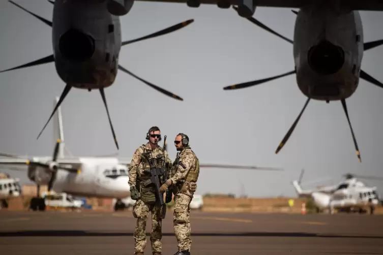 Deutsche Soldaten in Mali stehen am Flughafen in Gao und sichern ein Transportflugzeug.