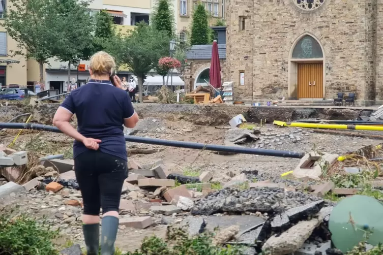 Nach dem Hochwasser in Bad Neuenahr steht eine Frau vor den Trümmern und telefoniert mit ihrem Handy. 