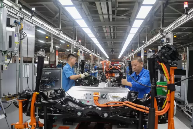 Fahrzeugbauer in einer Werkshalle an einer Produktionslinie von SAIC Volkswagen in Shanghai.