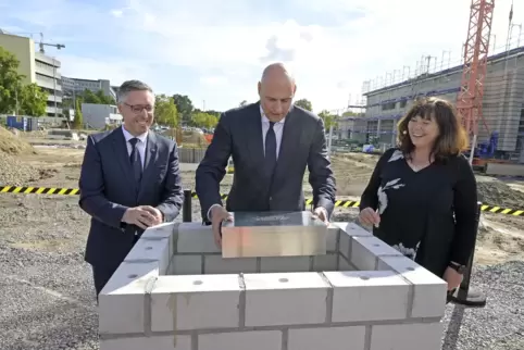 Jutta Steinruck, Dennis Fanelsa und Christoph Oberlinner (oben, von rechts) mit der Zeitkapsel, die in das Gebäude eingebaut wir