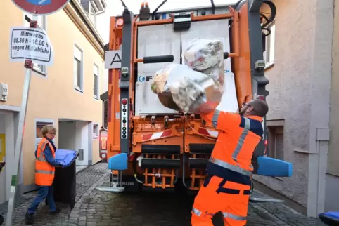Mit Schwung: Lader Patrick Rupp wirft Müllsäcke ins Fahrzeug, Irmgard Münch-Weinmann karrt eine Papiertonne heran. Mit Schwung: Lader Patrick Rupp wirft Müllsäcke ins Fahrzeug, Irmgard Münch-Weinmann karrt eine Papiertonne heran.