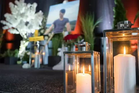 Kerzen, ein Portrait und ein Kreuz mit dem Namen des getöteten Tankstellen-Mitarbeiters stehen bei der Trauerfeier auf der Bühne