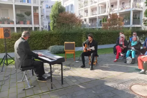 „Besser als nichts“: Paata Demurishvili spielt in der Paul-Klee-Straße Piano, Jörg Teichert Gitarre vor zahlreichen Balkonen.