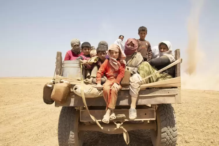 Das Foto aus der Ausstellung zeigt, wie jesidische Kinder vor dem IS auf den Berg Sinjar fliehen. 