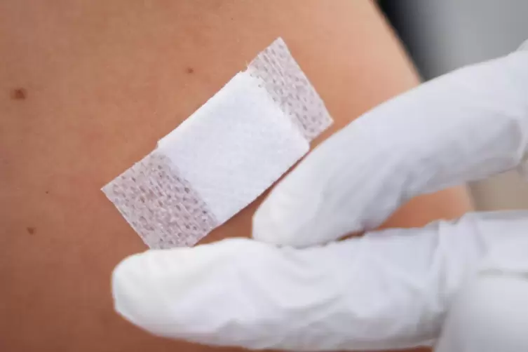 Eine Ärztin klebt nach einer Corona-Impfung ein Pflaster auf den Arm