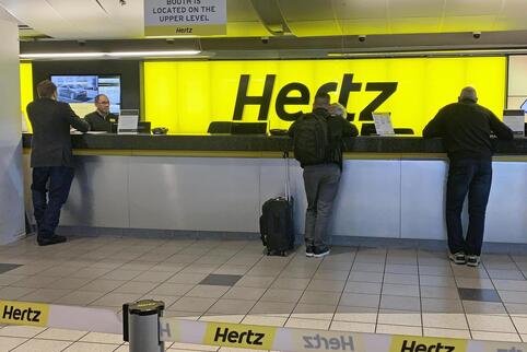 „Elektroautos sind nun Mainstream“, erklärte Hertz: Kunden am Schalter in einer Station des Autovermieters. 