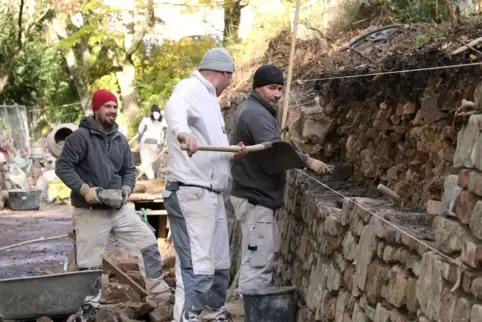 Maurer tragen die Mauer abschnittsweise ab und richten sie neu auf. 
