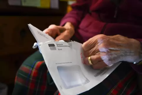 Eine Seniorin hält ihren Rentenbescheid in der Hand. 