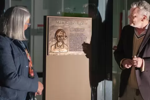 Lehrerin Eleonore Beinghaus und Künstler Franz Leschinger präsentieren die an einer Stele befestigte Bronzeplakette von Grete He