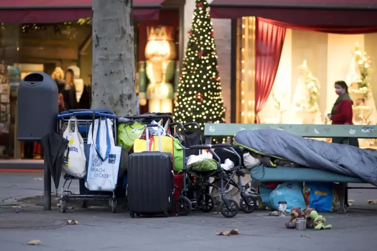 Welten entfernt: Lager eines Obdachlosen vor glitzerndem Konsum. Die Landesregierung will etwas gegen Wohnungslosigkeit tun.