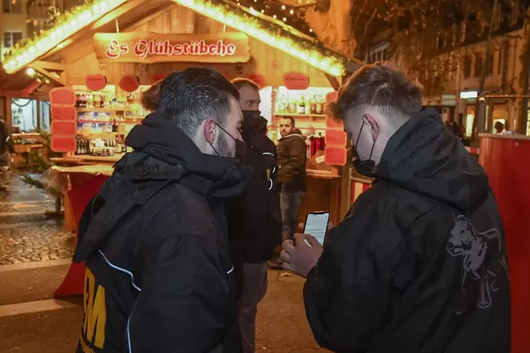 Prüfender Blick aufs Smartphone: Wer ins Budendorf auf dem Rathausplatz möchte, muss nachweisen, dass er geimpft oder genesen is