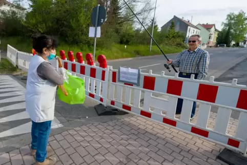 Verkäuferin Myriam Hansen-Boualit und Hartmut Fey mit Baguette und Angel an der 2020 gesperrten Grenze zwischen dem saarländisch