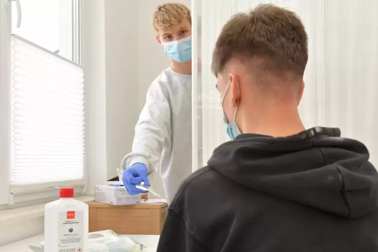 Thomas Rössler (hinten) überreicht einem Sportstudio-Besucher einen Coronatest. In dem Studio der Rösslers gibt es für den Selbs