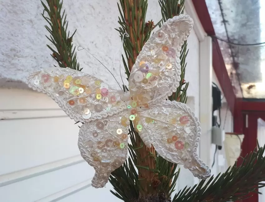 Unsere Baumspitze ziert ein Schmetterling. Auf dem immergrünen Tannenbaum symbolisiert er die Hoffnung, dass auf jeden dunklen W