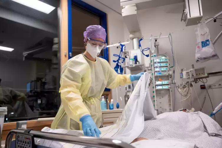 Eine Krankenpflegerin versorgt einen Covid-19-Patienten, der im künstlichen Koma liegt und beatmet wird. 
