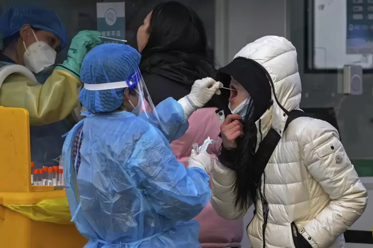 Eine Mitarbeiterin einer mobilen Coronavirus-Teststation entnimmt vor einem Bürogebäude einer Frau einen Abstrich für einen Coro