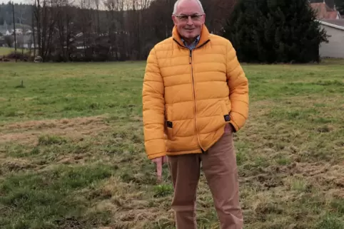 Werner Majunke, Bürgermeister von Carlsberg, zeigt auf einen Grenzpfosten und freut sich darüber, dass auf diesem Gelände bald d