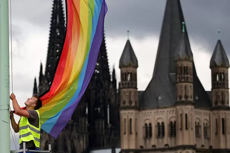 Ein Arbeiter hängt nach der Entscheidung im Bundestag über die „Ehe für alle" vor der Kulisse des Doms und der Kirche Groß St. M