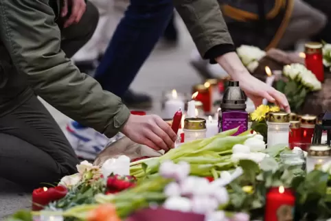 Baden-Württemberg, Heidelberg: Menschen legen vor einem Gebäude der Universität Blumen und Kerzen an den Wegesrand. 
