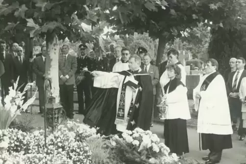 Pfarrer Hermann Groß segnet 1990 an Ludwig Nieders 70. Geburtstag dessen Grab auf dem Friedhof Bexbach. Im Hintergrund Gäste aus
