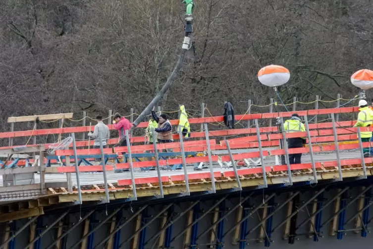 Eine Handvoll Arbeiter hat den Beton auf der Brückenoberfläche verteilt.