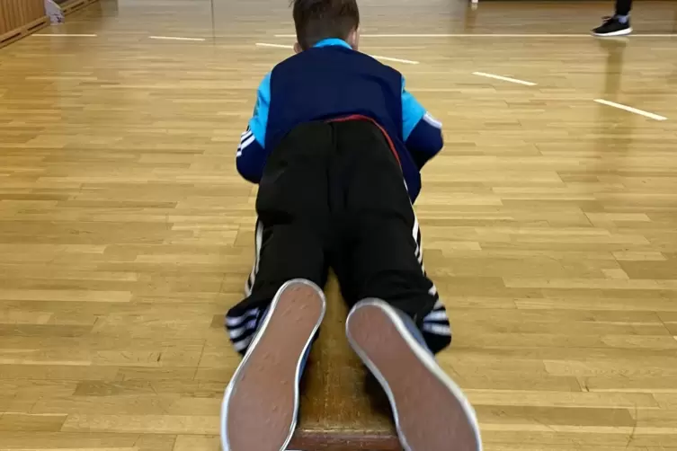 Kraftakt im Zirkeltraining: Mit den Armen zieht sich dieser Junge zum anderen Bankende.