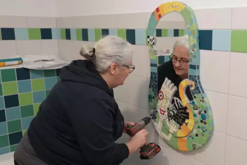Künstlerin Tanja Lebski bringt eines ihrer Werke in der Jungen-Toilette an.
