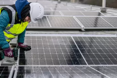 Ein Arbeiter installiert eine Photovoltaikanlage.