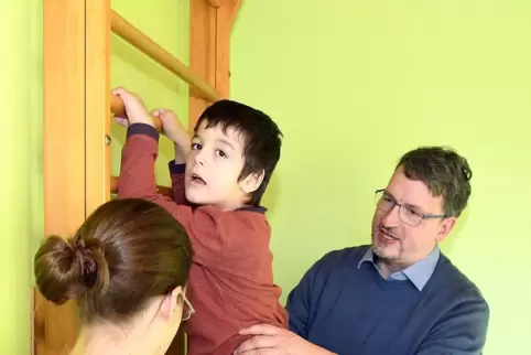 Helge Gallwitz unterstützt einen Jungen bei seinen Kletterübungen, assistiert von Nina Müller. 