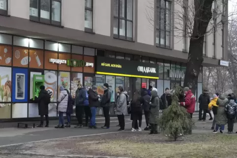 Menschen stehen in der ukrainischen hauptstadt Kiew Schlange vor einem Geldautomaten. 