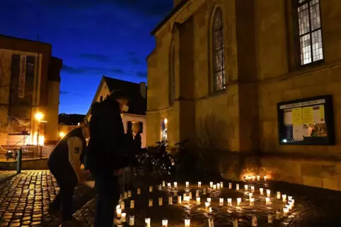 Vor der Kirche leuchteten Kerzen in Form des Friedenssymbols (unser Bild).