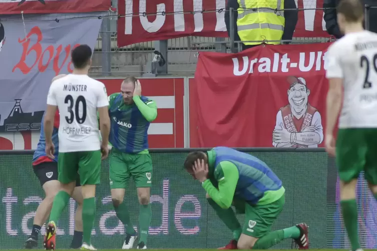 Idiotische Anhänger: Zwei Spieler von Preußen Münster machen sich vor dem Essener Fanblock warm, direkt neben ihnen detoniert ei