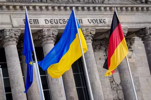 Die Fahne der Ukraine (Mitte) weht am Sonntag vor dem Reichstagsgebäude in Berlin, dem Sitz des deutschen Bundestages, zwischen 