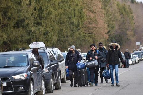 Menschen sind neben der Autoschlange auf dem Weg zum Checkpoint Shehyni unterwegs, um die ukrainisch-polnische Grenze zu überque