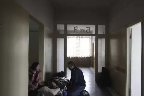 Menschen neben einem durch Granatbeschuss verwundeten Mann in einer Klinik in Mariupol.
