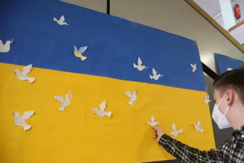 Ein Symbol der Hoffnung: Ein Schüler des Veldenz-Gymnasiums in Lautercken klebt eine Friedenstaube auf die Ukraine-Flagge. 