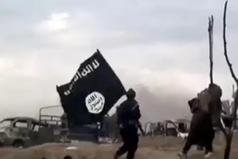 Syrien, Baghus: IS-Kämpfer laufen mit einer IS-Flagge. 