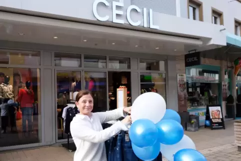 Filialleiterin Anne Breda-Fasske dekoriert einen Hosenständer mit Luftballons.