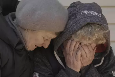 Eine Frau wird getröstet, die in Butscha um getötete Angehörige trauert.