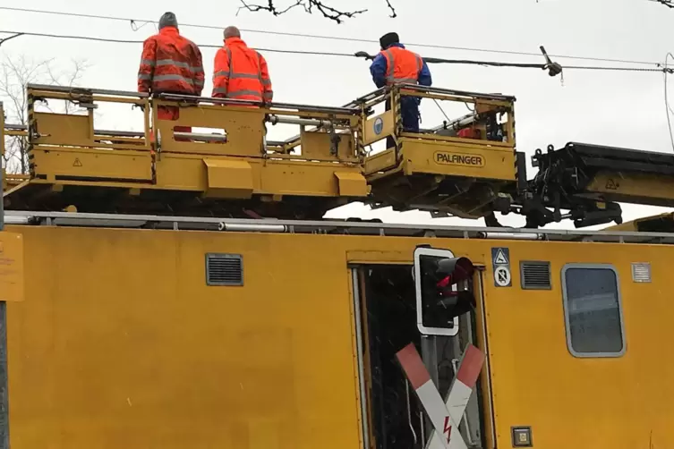 Auf dem Dach des Zuges sind Leute mit der Reparatur der Oberleitung besch&auml;ftigt. Immer mal wieder f&auml;hrt er vor und zur&uuml;ck.