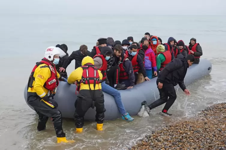 Mitglieder einer Rettungsbootbesatzung helfen Menschen, bei denen es sich vermutlich um Migranten handelt, aus einem Schlauchboo