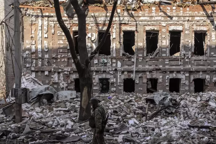 Ein ukrainischer Soldat geht vorbei an Trümmern durch Beschuss zerstörter Gebäude in Charkiw.
