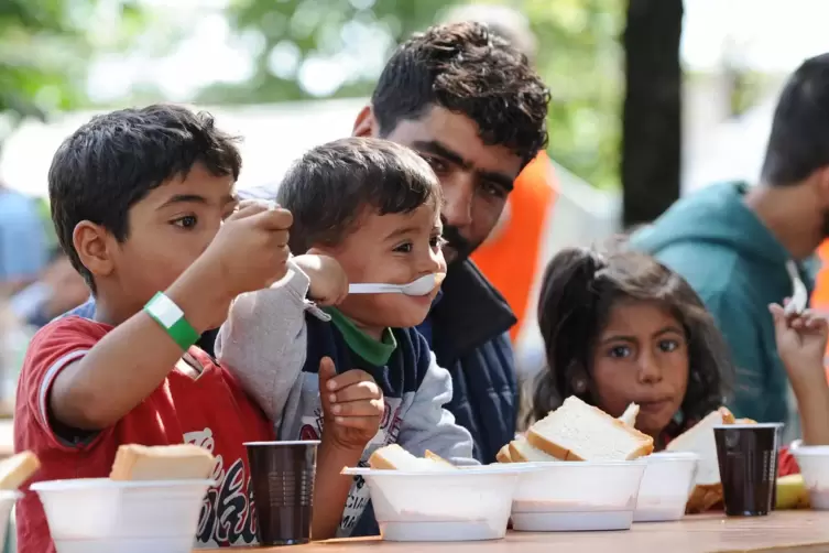 Flüchtlinge aus Syrien sitzen am im September 2015 kurz nach ihrer Ankunft in einem Zeltlager in München und essen. Auch damals 