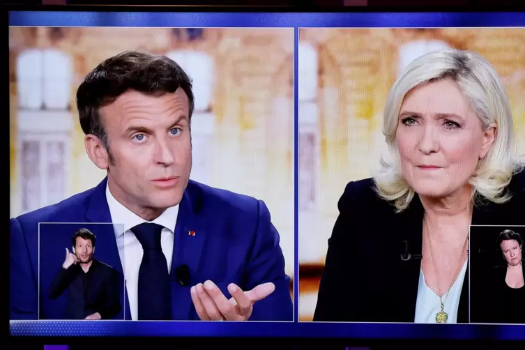 Die Aufnahme zeigt Fernsehbildschirme mit der Live-Übertragung einer TV-Debatte zwischen Emmanuel Macron (links), Präsident von 