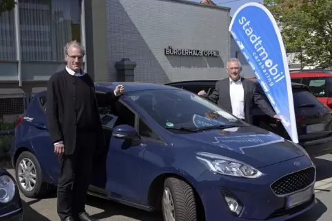 Dezernent Thewalt (links) und Dieter Netter präsentieren den Leihwagen am Bürgerhaus.