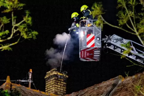 Die Feuerwehr kehrte von der Drehleiter aus mit einem Stahlbesen den glimmenden Ruß aus dem Kamin.